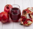 side view glass of pomegranate juice with pomegranates on white background